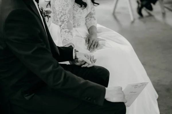 新娘和新郎手牵手坐在一起的一张灰度特写照片 — 图库照片