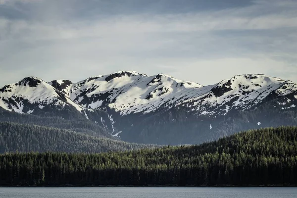 Corpo Água Com Uma Costa Florestada Montanhas Cobertas Neve Vistas — Fotografia de Stock