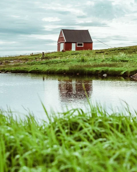 Pionowe Ujęcie Drewnianego Domu Trawiastym Brzegu Jeziora Norwegii — Zdjęcie stockowe