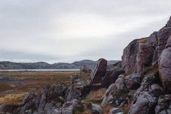 俄罗斯摩尔曼斯克科拉河畔草地海岸灰蒙蒙的天空下的岩石悬崖景观 — 图库照片