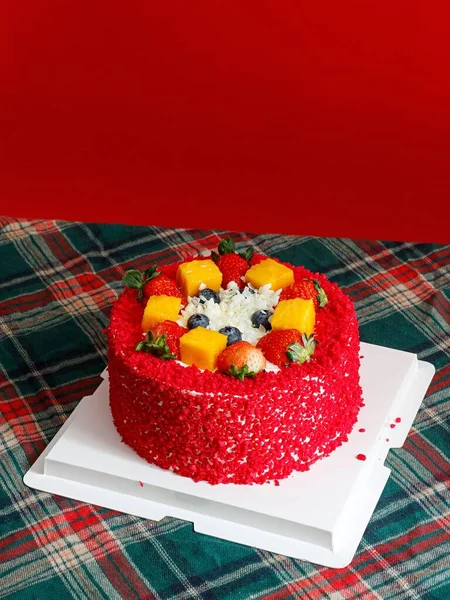 一个垂直拍摄的红色天鹅绒蛋糕装饰着浆果在桌子上 — 图库照片