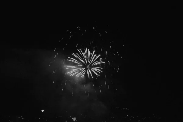 暗い背景と街並みを背景にした素晴らしいカラフルな新年の花火のグレースケール — ストック写真