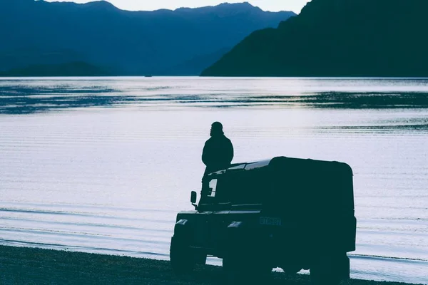 Una Silueta Hombre Sentado Coche Junto Borde Lago Con Montañas —  Fotos de Stock