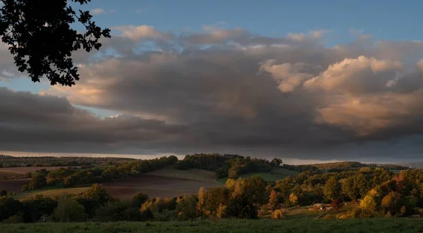 雲に覆われた空に対する村の緑のフィールドの風景 — ストック写真
