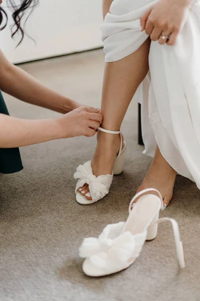 花嫁が彼女の靴を着るのを助ける少女の垂直ショット — ストック写真