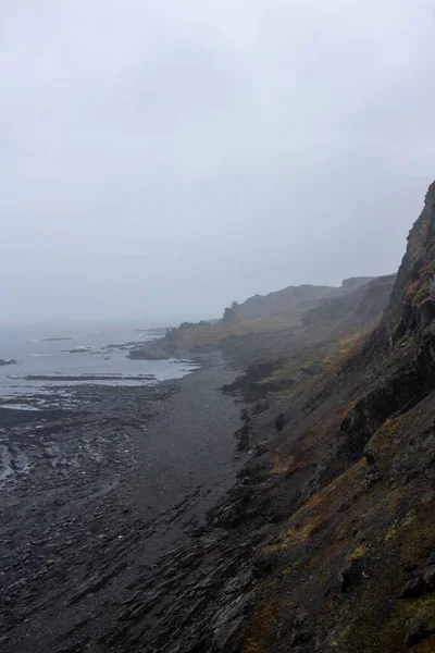 一个岩石悬崖峡谷海岸在海边 雾蒙蒙的天空在地平线上 垂直拍摄 — 图库照片