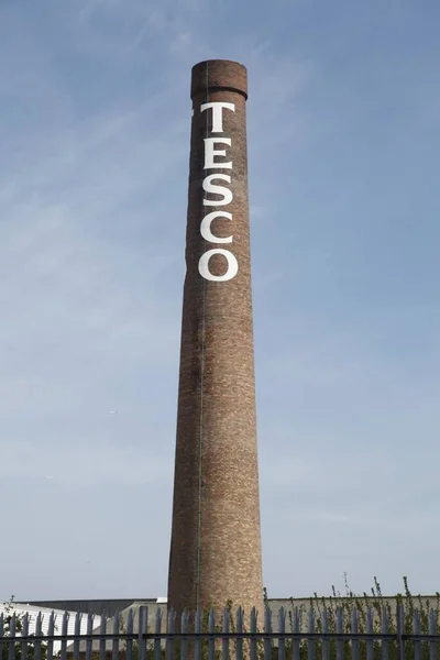 英国纽卡斯尔的一个巨大烟囱上挂着一幅特易购 Tesco 彩绘标志的垂直照片 — 图库照片