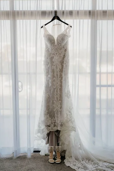 Вертикальный Снимок Красивого Кружевного Свадебного Платья Вешалке Висящей Окне — стоковое фото