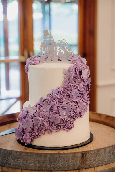 紫色の花と蝶の装飾が施された白いウェディングケーキの垂直ショット — ストック写真