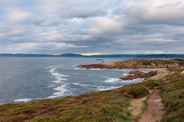 Kasvetli bir günde rüzgarlı bir denizde yüksek açılı bir manzara ve etrafında sarı otlar, Galiçya, İspanya