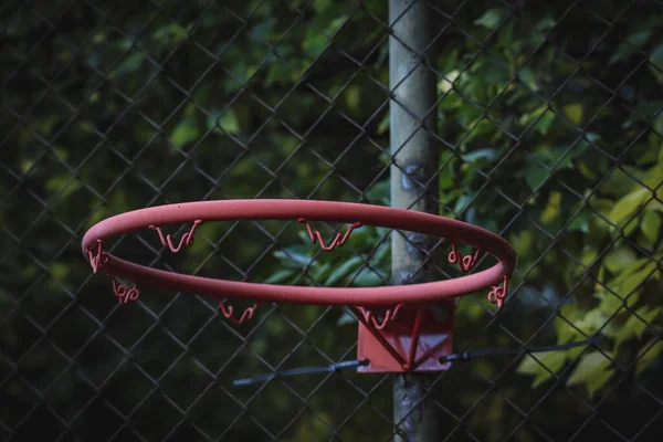 一个没有网的旧篮球圈的特写镜头 挂在室外场地的金属格栅上 — 图库照片