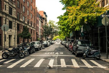 New York 'ta park halindeki arabaların, ağaçların ve binaların olduğu güzel bir yol.