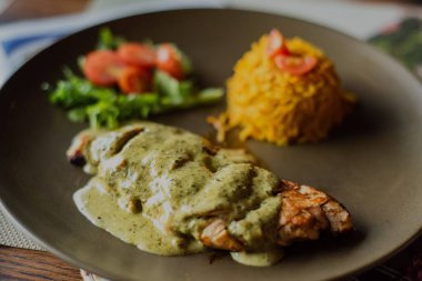 Meksika yeşil piyano sosunda balık ve restoranda servis edilen pirinçle yakın plan bir yemek.