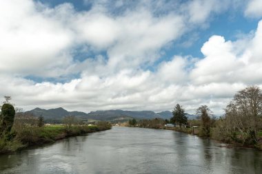 Nehalem Nehri 'nin üzerinde bulutların altında sonbahar ağaçlarıyla çevrili manzaralı bir çekim.