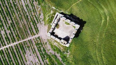 Tarım alanının ortasındaki bir taş saat kulesinin havadan çekilmiş görüntüsü.