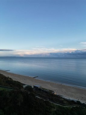 Arka planda bulutlu gökyüzü olan plaj manzaralı yüksek açılı bir deniz manzarası.