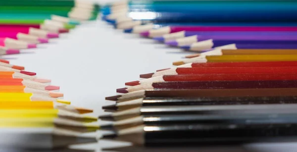 An image of colorful pencils lined up face to face on the white background