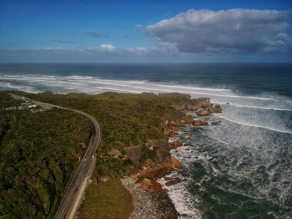 stock image A high-angle view of a Pancake Rocks Lookout near the sea full of bubbly waves under the blue sky