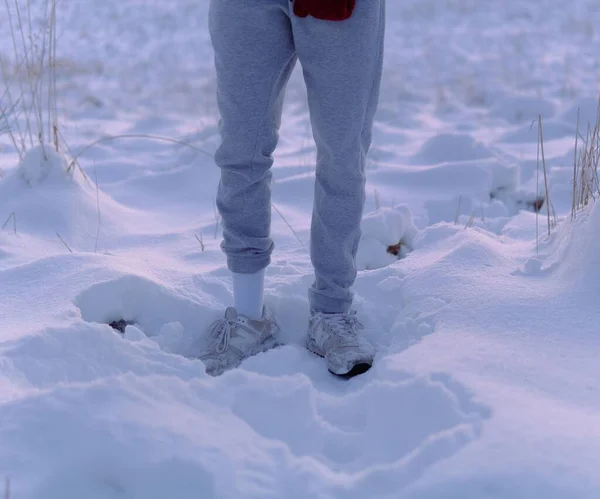 背景の白雪の中にグレーのスウェットパンツを穿いている人の下の部分 — ストック写真