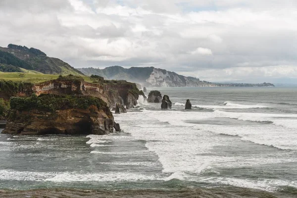 曇り空の下で巨大な岩をクラッシュ海の泡波のドローンショット — ストック写真