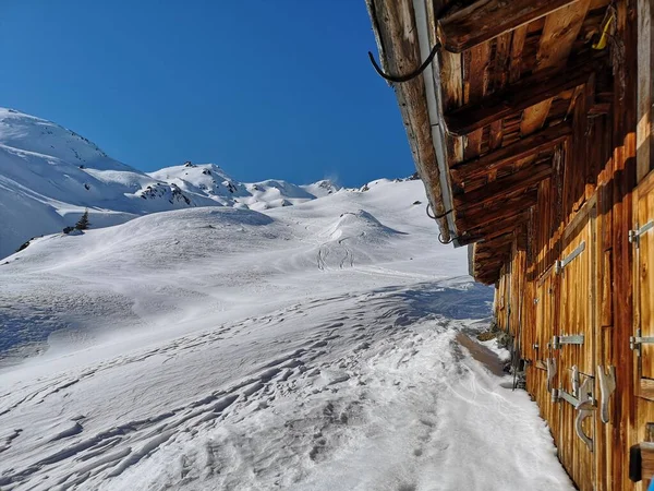 青空を背景に冬の雪山の上に建つ木造建築 — ストック写真