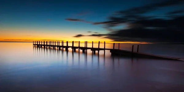 Eine Langzeitbelichtungsaufnahme Eines Pier Meer Bei Sonnenuntergang — Stockfoto