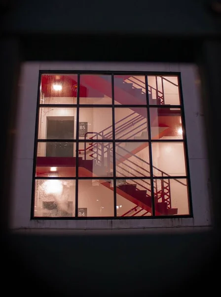一道红色的垂直楼梯 从正方形的窗户上可以看到有窗户守卫的楼梯 — 图库照片