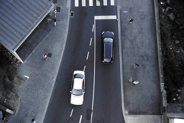 在人行横道上 白色和黑色汽车向相反方向行驶的空中俯瞰图 — 图库照片