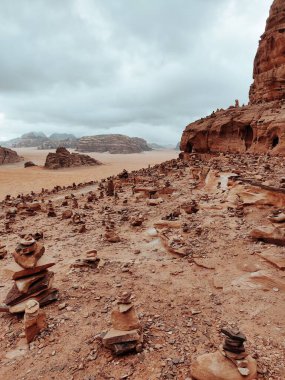 Wadi Rum rezervindeki kumtaşı oluşumlarının dikey çekimi bulutlu gökyüzünün altında