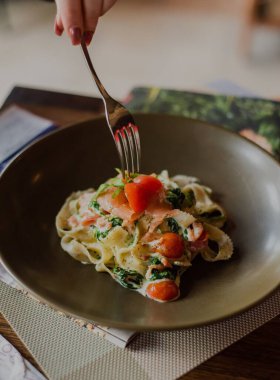 Vişne soslu tagliatelle makarnası, çatalla yemek yiyen kadın eli.