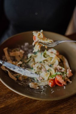 Vişne soslu tagliatelle makarnası, çatalla yemek yiyen bir kadın eli.