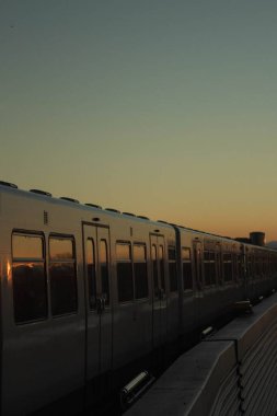 Güzel, sakin bir günbatımında, platformda bir trenin dikey çekimi.