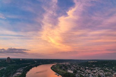 Renkli bir günbatımı sırasında binalarla çevrili şehir nehrinin manzarası.