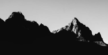 Güneş ışığında kayalık dağların tepelerinin gri pulu