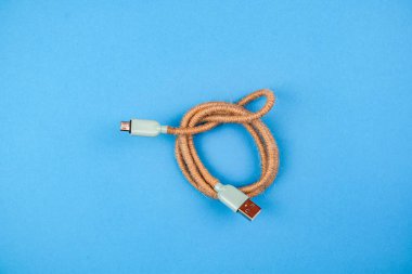 Mavi bir arkaplanda izole edilmiş kahverengi bir USB kablosunun üst görüntüsü