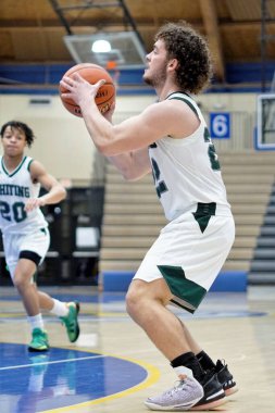 Genç beyaz bir basketbolcu topa vuruyor