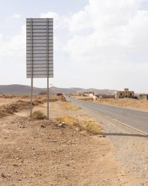 Kırsal bir yolun dikey görüntüsü ve Fas 'ın arka planında tepeler olan büyük bir afiş.