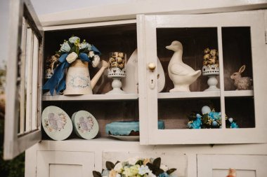 Paskalya süslemesi için raftaki çiçekler, kurabiyeler ve pastalar.