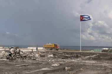 Zarar görmüş Küba bayrağıyla enkaz taşıyan dolu bir kamyon.
