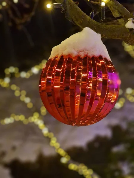 光のクリスマスツリーに掛けられた赤い装飾の選択的な焦点ショット — ストック写真