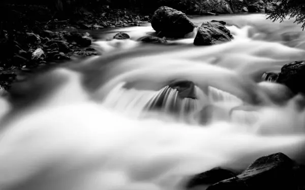 Długie Monochromatyczne Ujęcie Wodospadu Przepływającego Przez Skały Kamienie — Zdjęcie stockowe