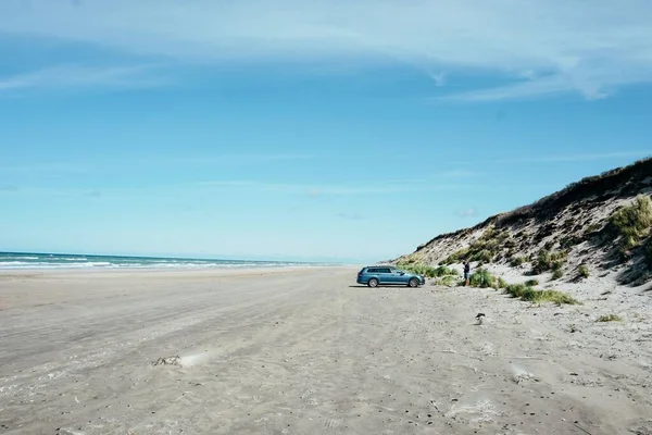 해변에 자동차가 바다에 둘러싸인 채푸른 구름낀 하늘을 배경으로 — 스톡 사진