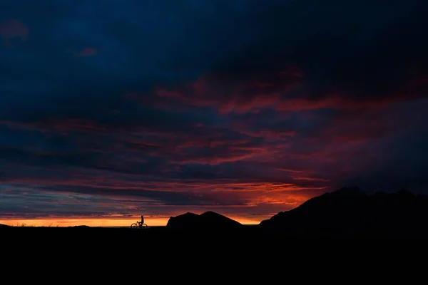 Ein Wunderschöner Sonnenuntergangshimmel Über Den Silhouetten Eines Radfahrers Und Hügeln — Stockfoto