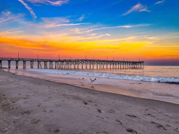 夕暮れ時の砂浜の木製の桟橋 — ストック写真