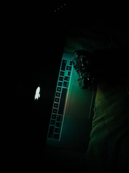 在黑暗中垂直拍摄的苹果笔记本电脑和相机 — 图库照片