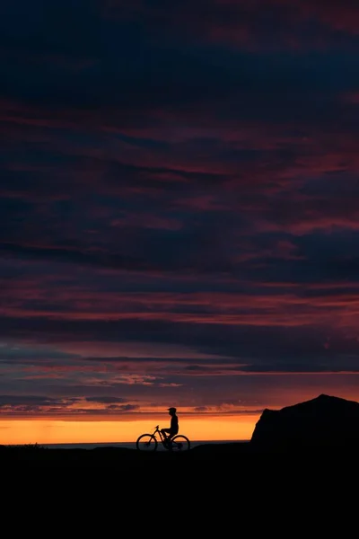 在骑自行车和爬山的人的轮廓上垂直拍摄的日落的天空 — 图库照片