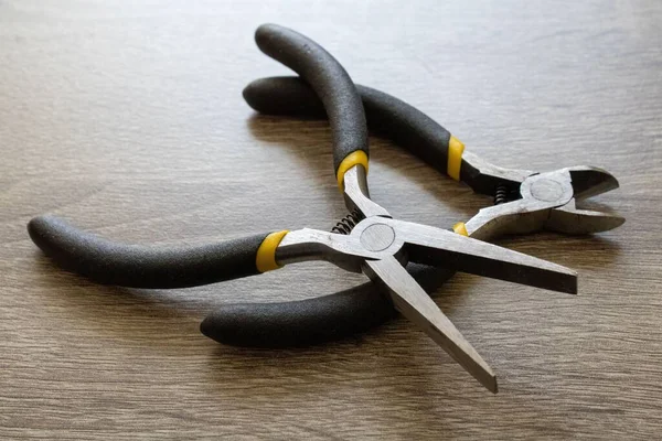 A closeup of flat nose pliers and wire cutter pliers on a table