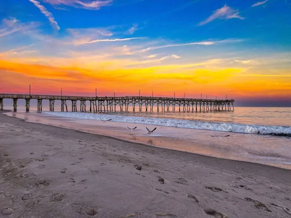 夕日の砂浜にある木製の桟橋 — ストック写真