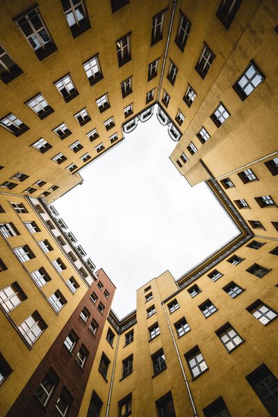 A vertical low-angle shot of the sky seen through yellow tall residential buildings