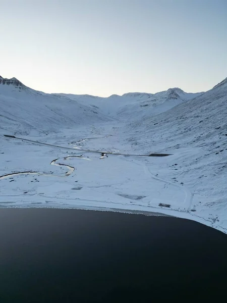 空中俯瞰着白雪覆盖的海岸和漆黑的湖面 Hedinsfjordur 冰岛荒废的峡湾 — 图库照片